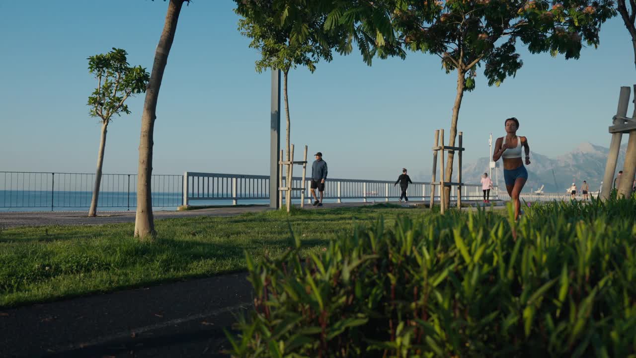 女子运动员在日落海滩慢跑。健身跑者女孩在海边训练，在美丽的日落或日出在夏天全身长度。缓慢的运动。高品质4k画面视频下载