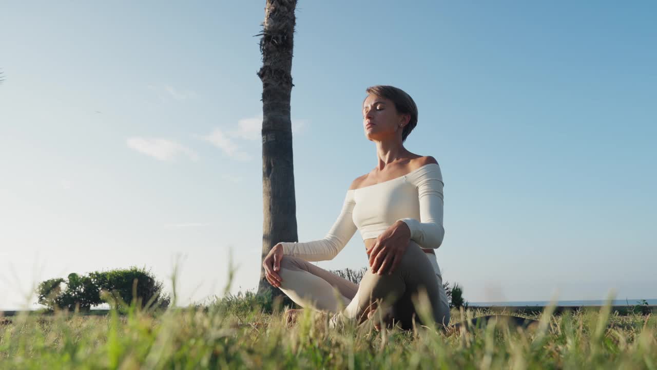 年轻的健身女性在沙滩上练习瑜伽，健康的生活方式理念。视频下载