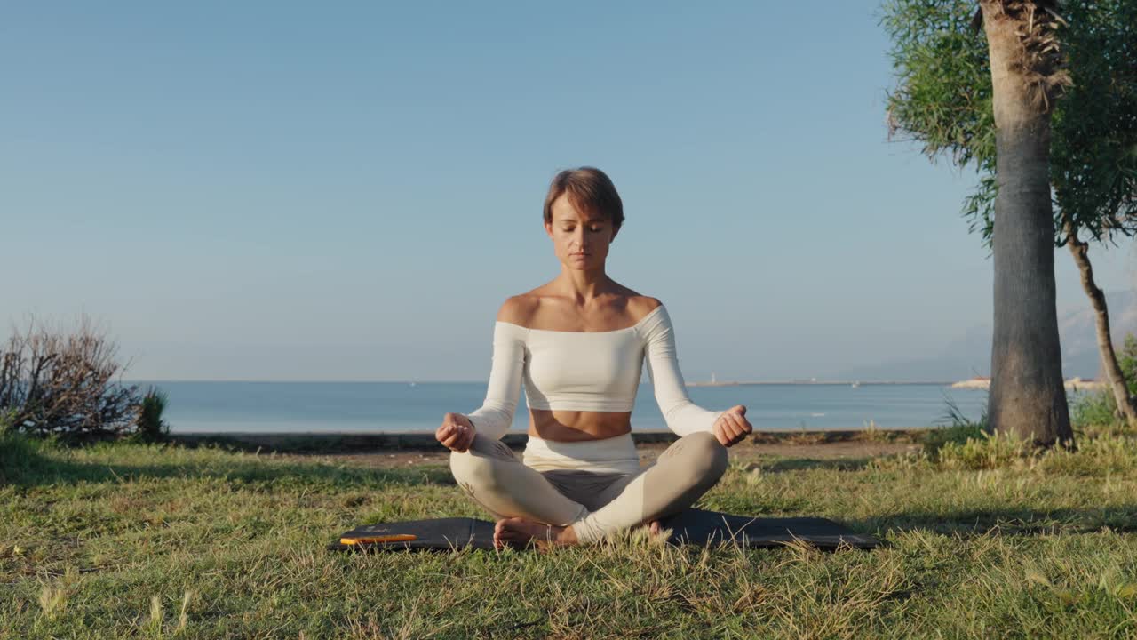 年轻的健身女性在沙滩上练习瑜伽，健康的生活方式理念。视频下载