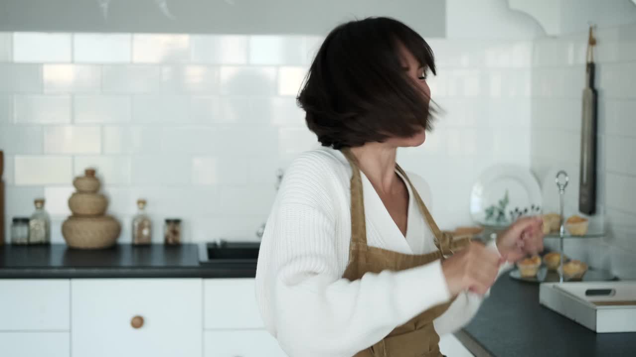 穿着围裙的快乐女人在厨房里无忧无虑地跳舞视频素材