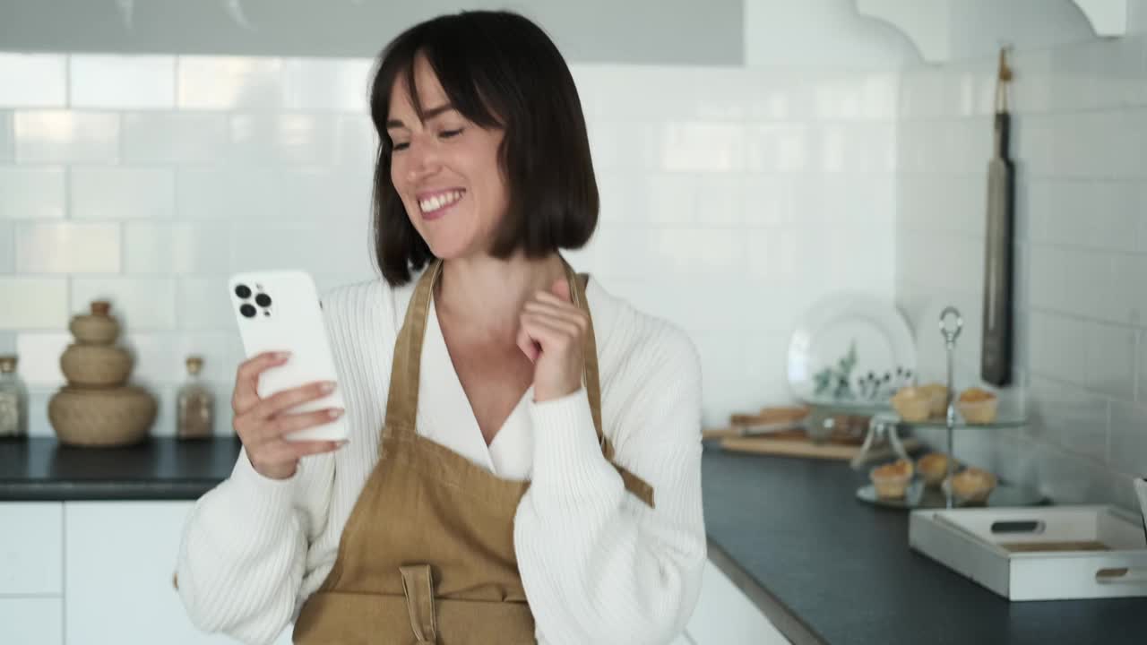 白种女人用手机在厨房跳舞视频素材
