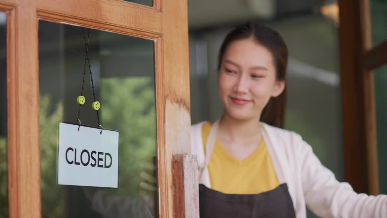 新开咖啡馆或餐厅的亚洲女性老板转身在门上打开标志视频素材