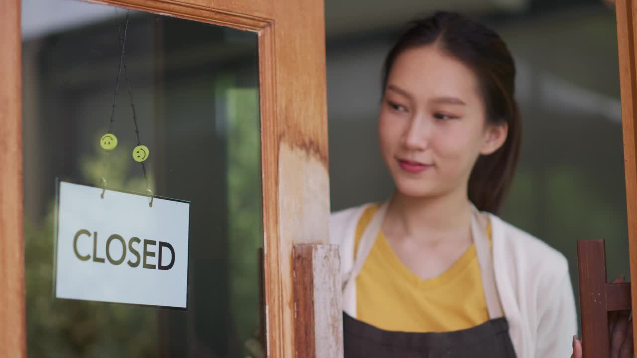 新开咖啡馆或餐厅的亚洲女性老板转身在门上打开标志视频素材