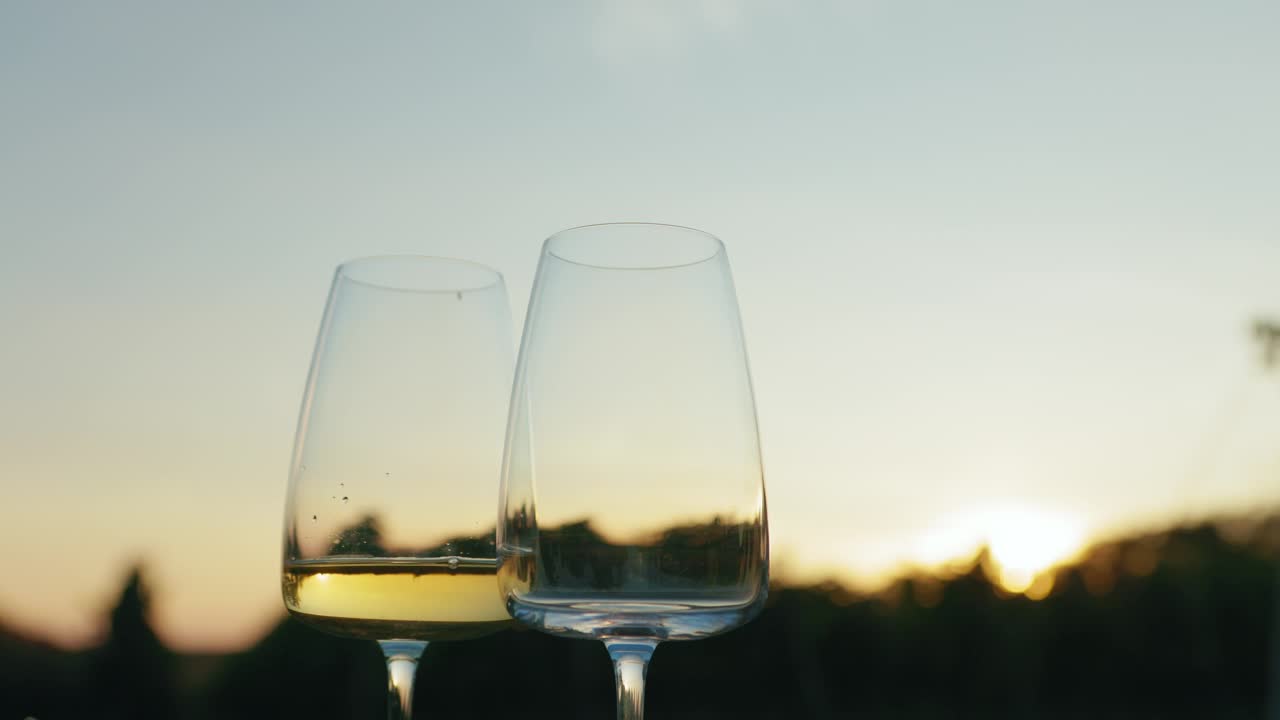 黄昏时分，葡萄园外的白葡萄酒倒进玻璃杯里视频下载