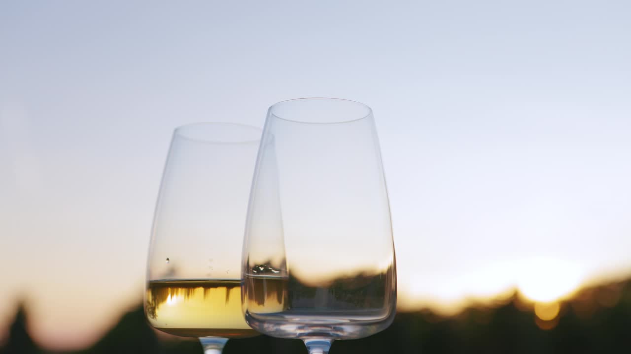 日落时分，葡萄园里的白葡萄酒倒进玻璃杯里视频下载