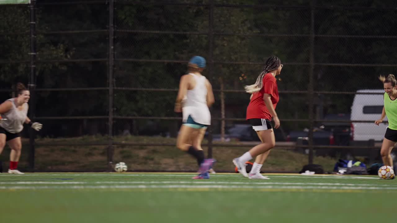 微笑的年轻女子在晚上进行球队足球训练视频下载
