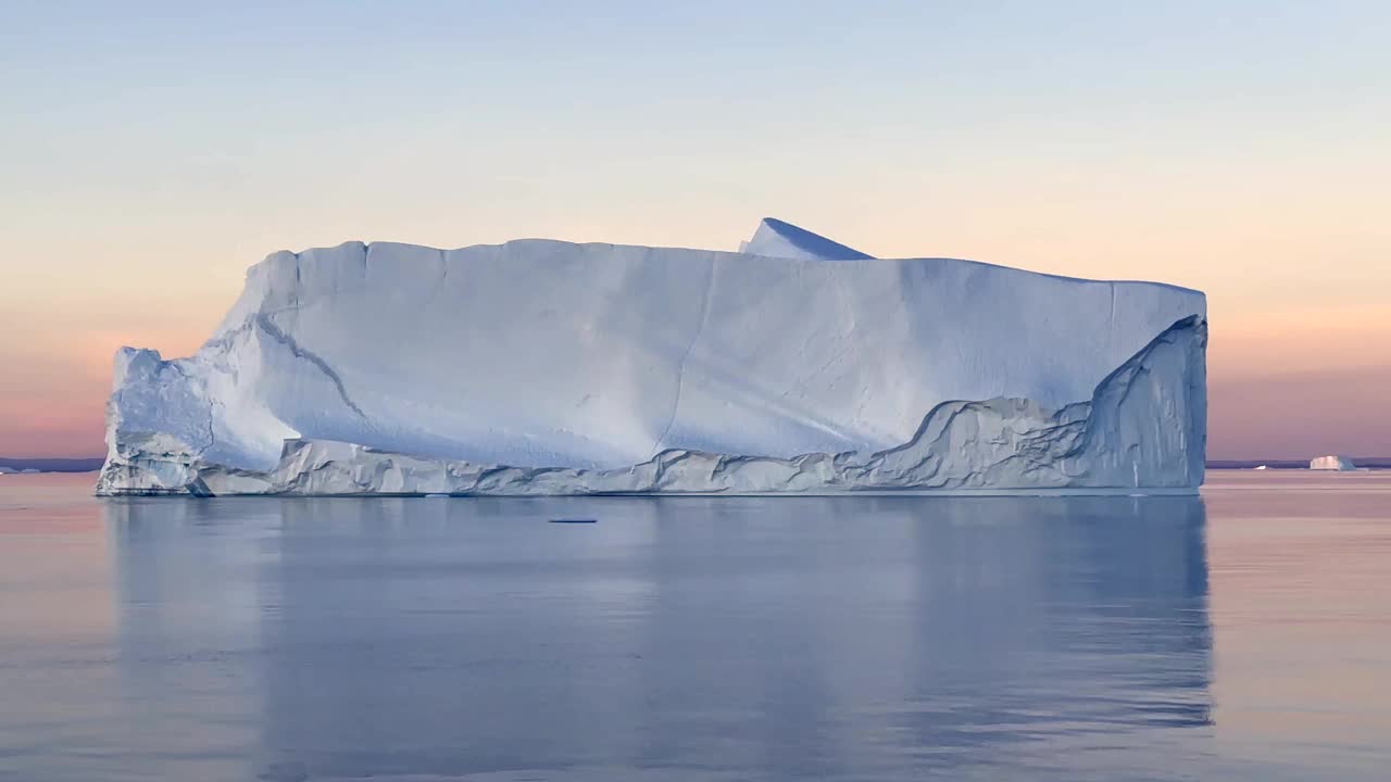 在北维斯特峡湾日落后反射出美丽的蓝色冰山。美丽的倒影。Scoresbysund,格陵兰岛视频下载