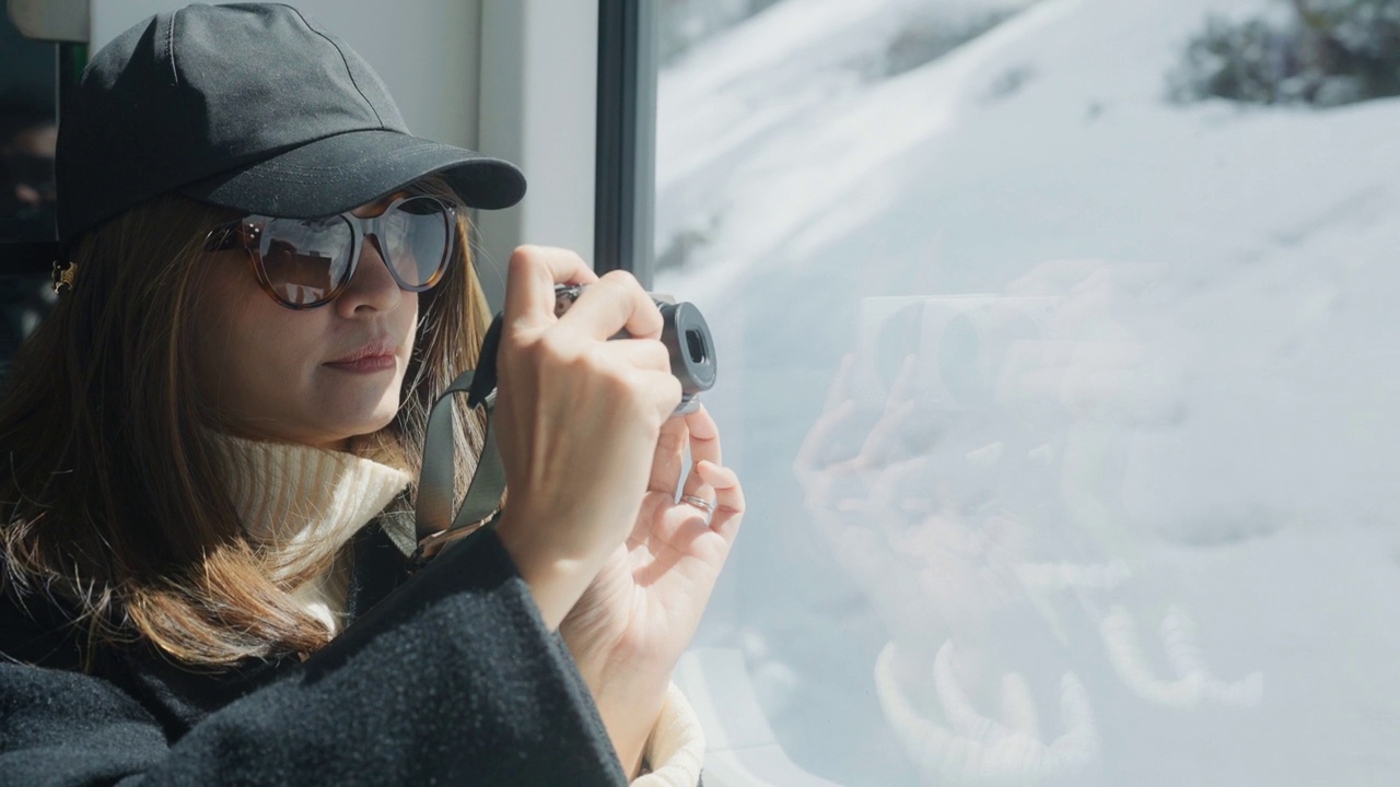 一位亚洲女摄影师在瑞士山区乘火车旅行时，正在拍摄美丽的山景。视频下载