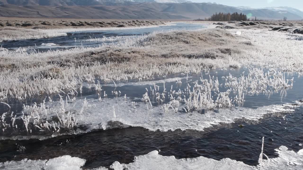 湍急的河流沿着冰冻的河岸奔流。秋山景观视频下载