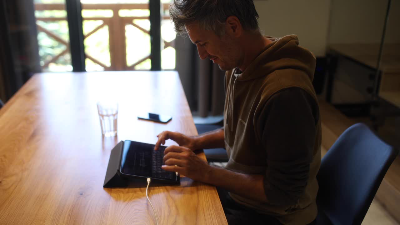 一名男子一边使用平板电脑一边通过电缆充电视频下载
