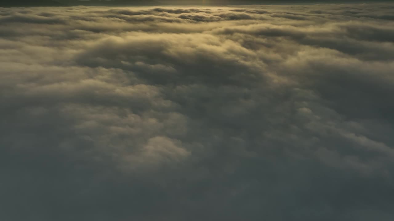 空中无人机视图向前飞行，倾斜，揭示美丽的日出在雾的海洋视频下载