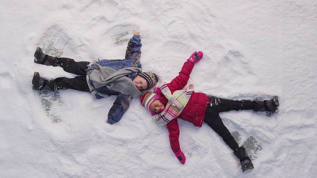 两个孩子在冬天做雪天使视频素材