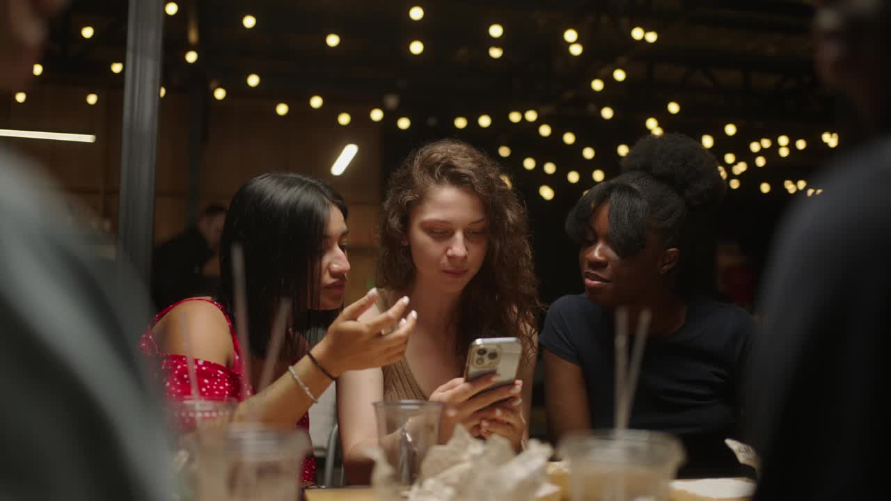 快乐的女人在智能手机上看有趣的照片，和朋友一起在餐馆吃饭视频下载