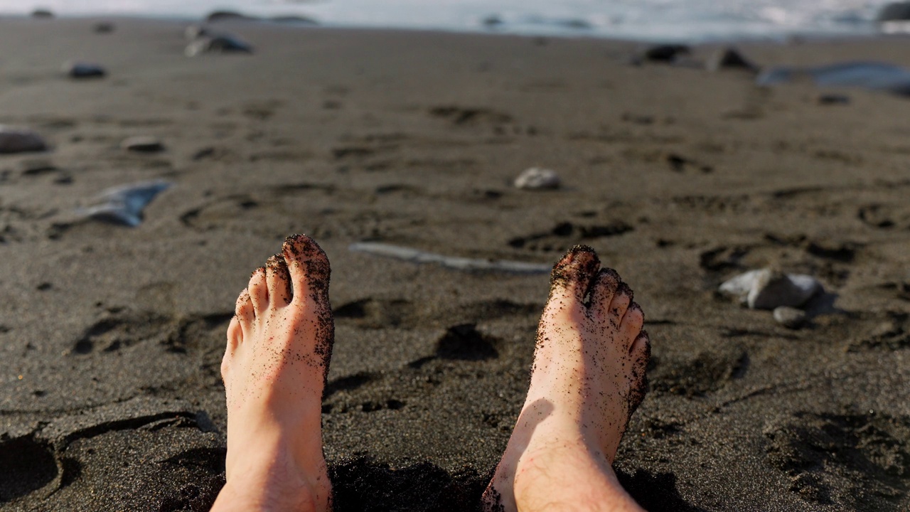 在特内里费岛的沙滩上，脚尖上有黑色的沙子视频下载