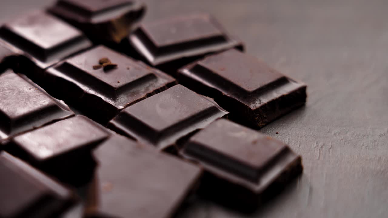 棕色板上碎黑苦巧克力块的特写。旋转视频下载