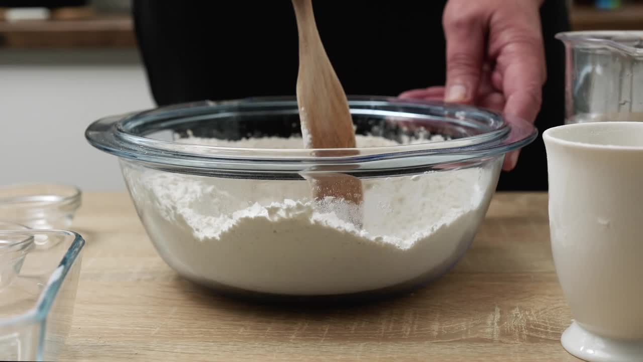 一名男子用手将盐和面粉混合在一起，准备制作美味的自制面包。视频素材