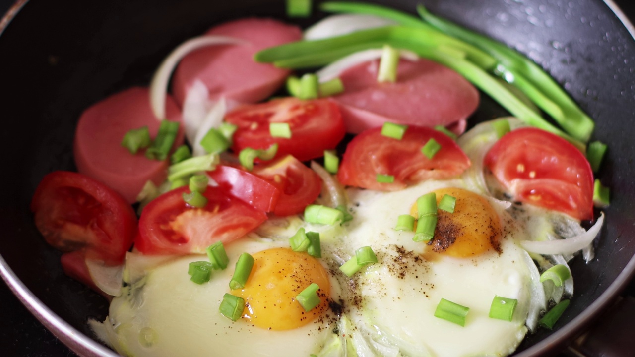 煎鸡蛋，用葱、西红柿、香料和香肠在平底锅里煎。早餐。乡村美食。4 k的决议视频下载