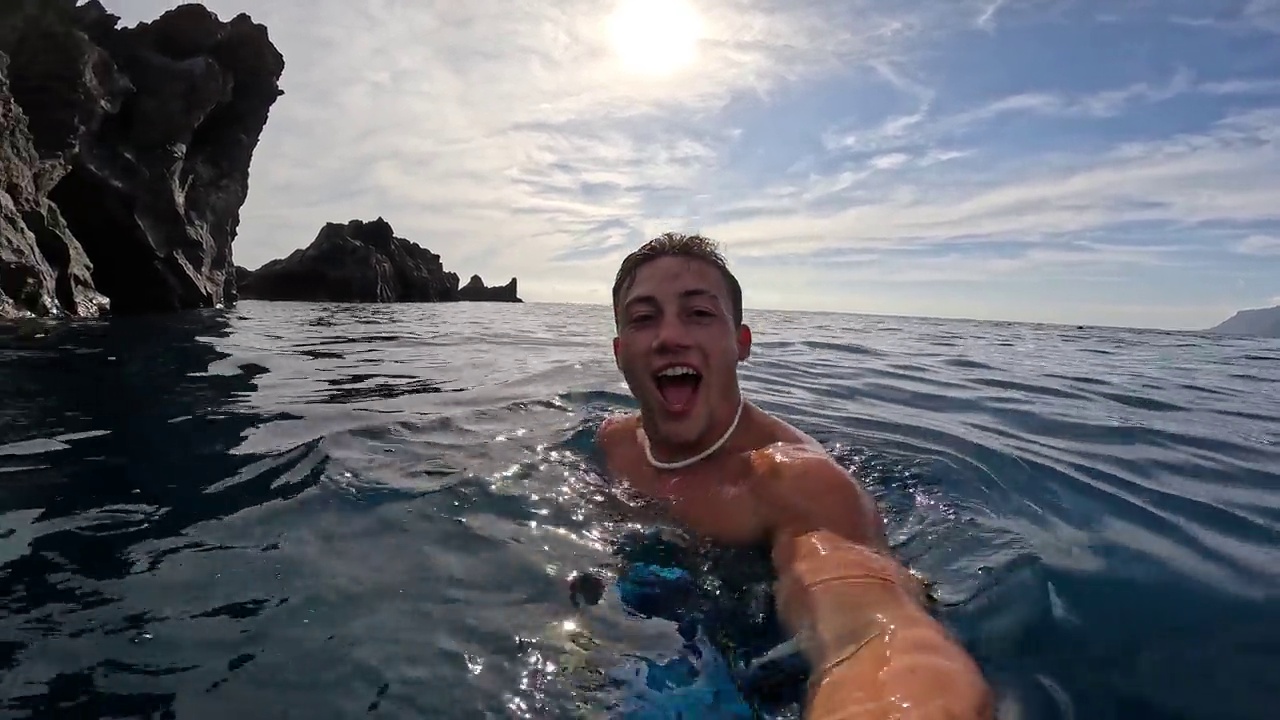 一个年轻的漂亮的活跃的男人游泳和享受户外假期在海上浮潜寻找鱼和珊瑚。男性旅行者拿着相机在蓝色的海洋里玩得很开心视频素材
