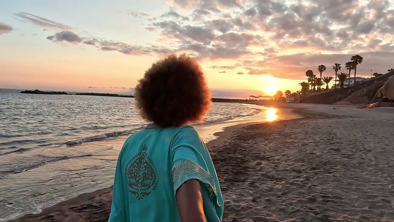 一个非洲多种族的年轻美女拿着相机在海滩上自拍，享受夏日户外度假。视频素材