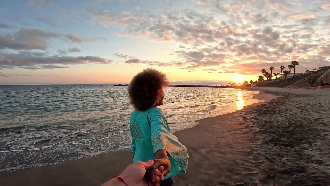 一个非洲多种族的年轻美女拿着相机在海滩上自拍，享受夏日户外度假。视频下载