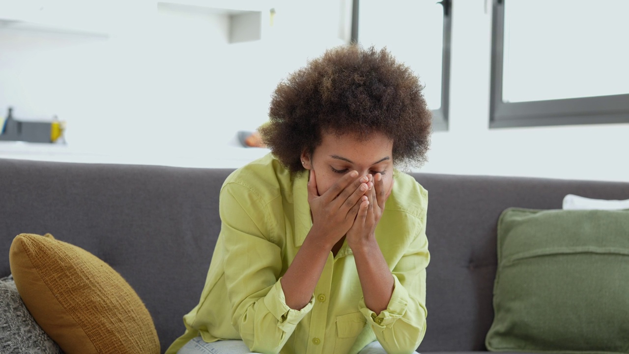 心烦意乱紧张的年轻非洲妇女按摩寺庙感到强烈的头痛概念，沮丧疲倦的黑人女孩触摸头痛头痛患偏头痛高血压坐在家里的沙发上视频下载