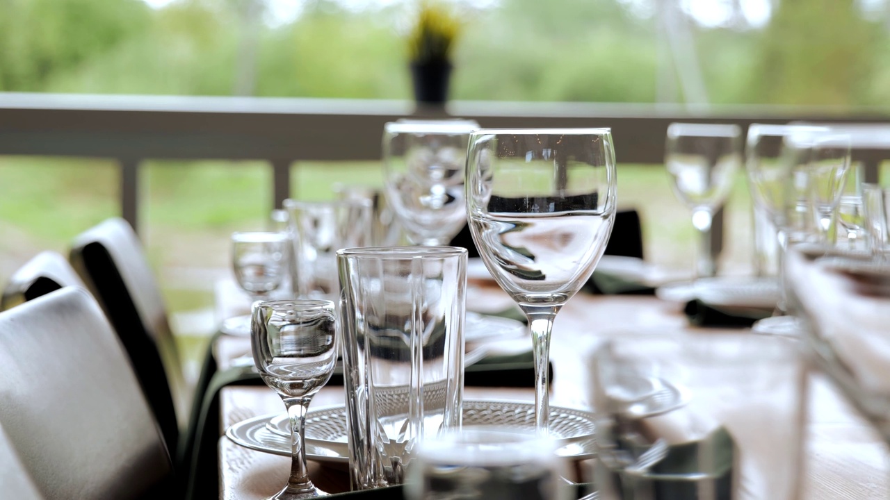 节日餐桌上的玻璃器皿。玻璃杯和酒杯放在桌子上。视频素材