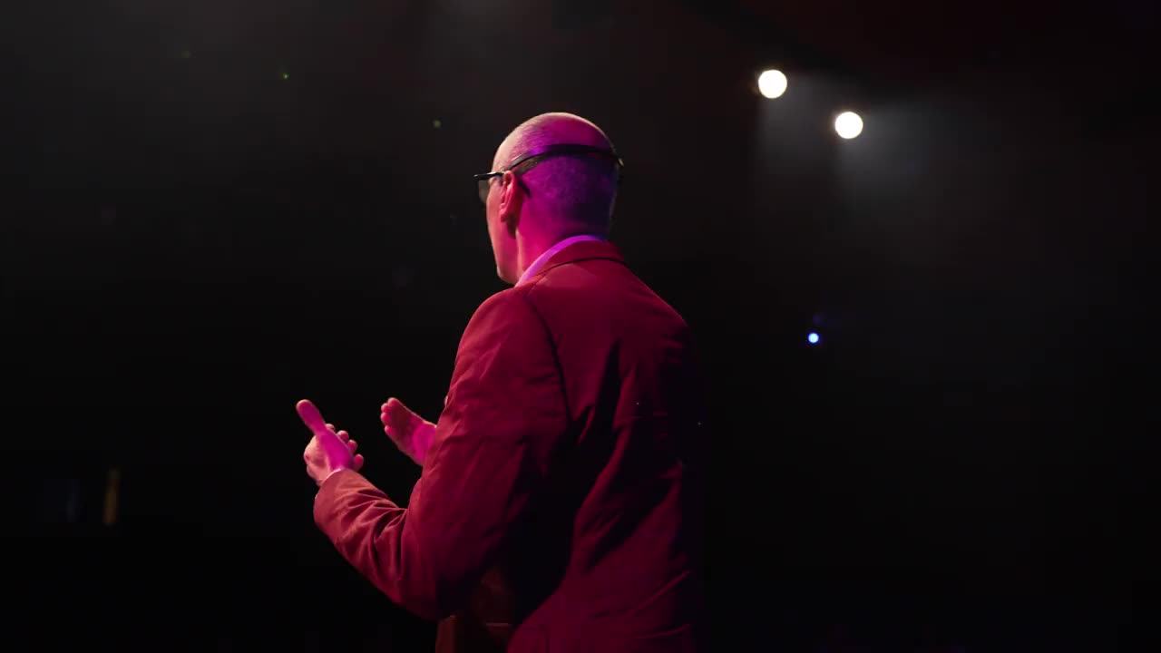 一名西装革履的男子在舞台上用头戴式麦克风讲话视频下载