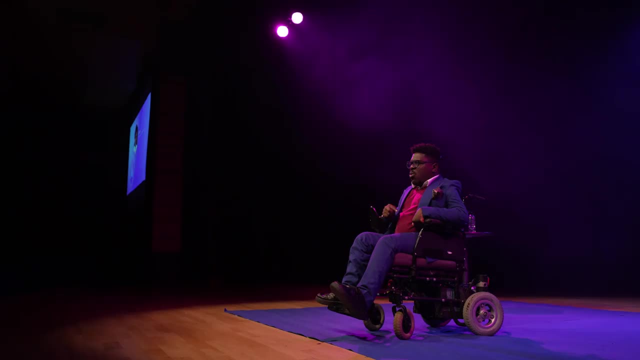 一个坐在轮椅上的人在观众面前演讲视频下载