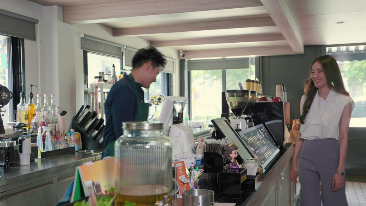 微笑的亚洲咖啡师自豪地在咖啡店提供咖啡视频下载