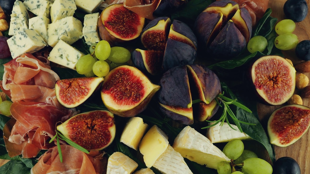 无花果、火腿、菠菜叶、葡萄、坚果和蓝纹奶酪放在一块木板上。零食。视频下载