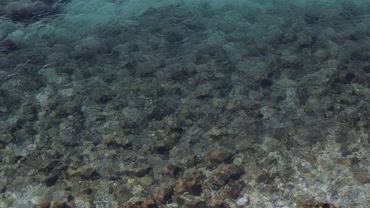 鸟瞰图，蓝色的海浪在底部的石头上视频下载
