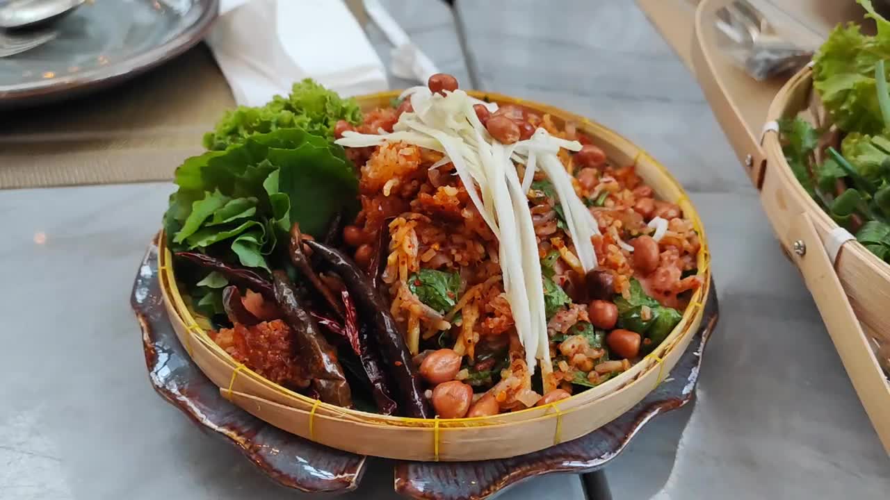 Yam Naem Khao Tod香辣猪肉沙拉香脆米饭，与蔬菜一起在回收纸盘中食用，泰国菜辛辣的开胃菜，由炒饭和辣椒酱混合腌制猪肉制成。视频下载