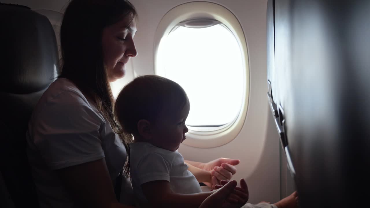 妈妈和孩子坐飞机，妈妈从窗户看风景视频下载