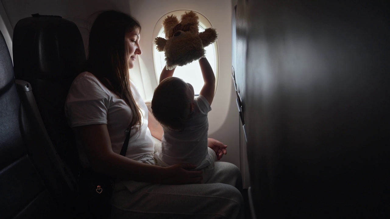 小女孩在飞机上玩妈妈怀里的玩具熊视频下载