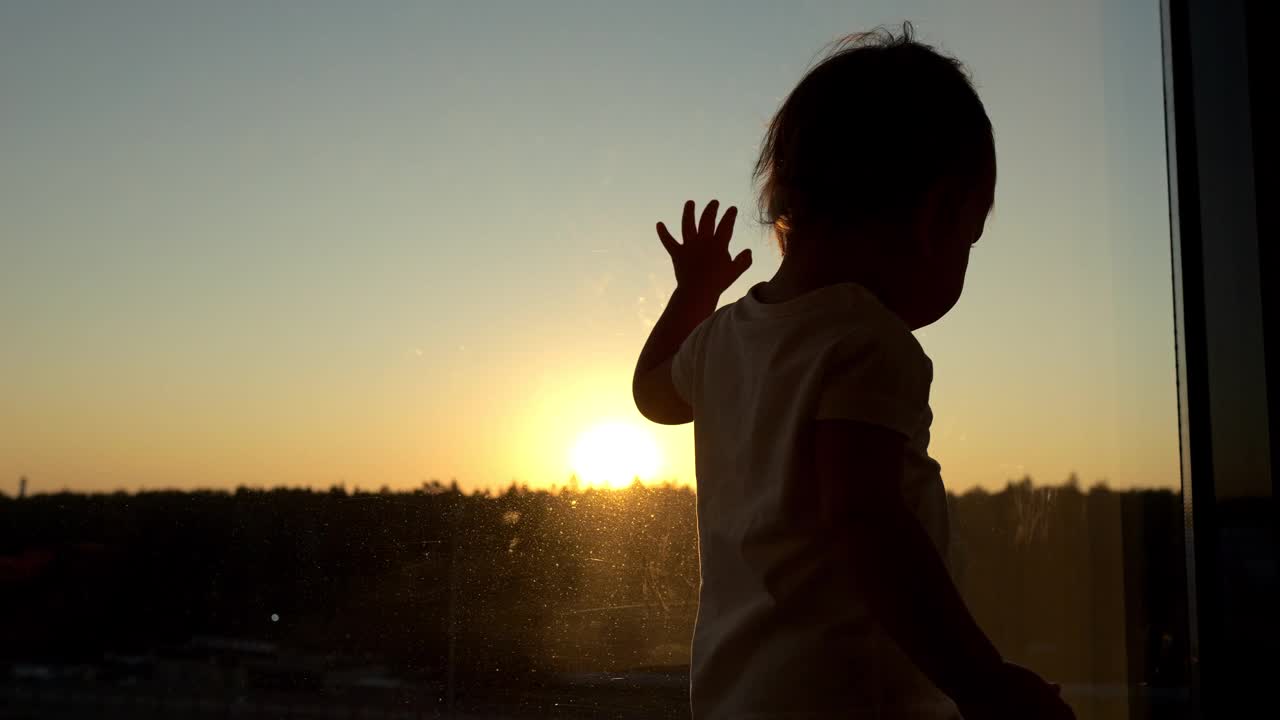 可爱的幼儿女孩在日落背景剪影视频下载