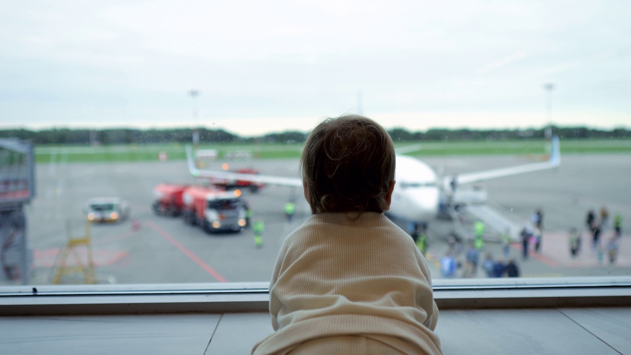 小孩透过大窗户看着飞机上的人视频下载