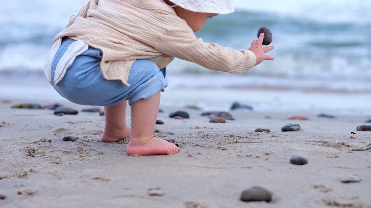 小女孩在沙滩上玩耍，把鹅卵石从一边扔到另一边视频下载