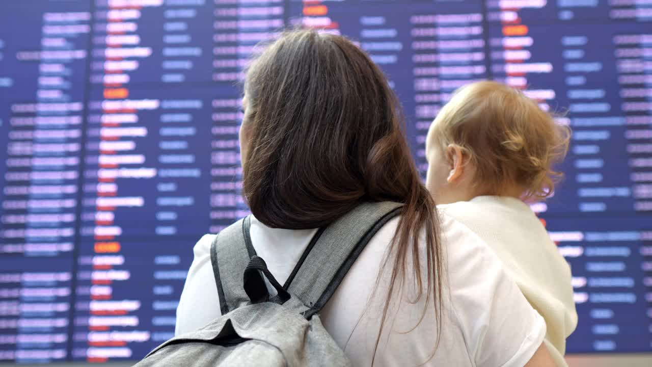 抱着孩子的妈妈站在机场看时刻表视频下载