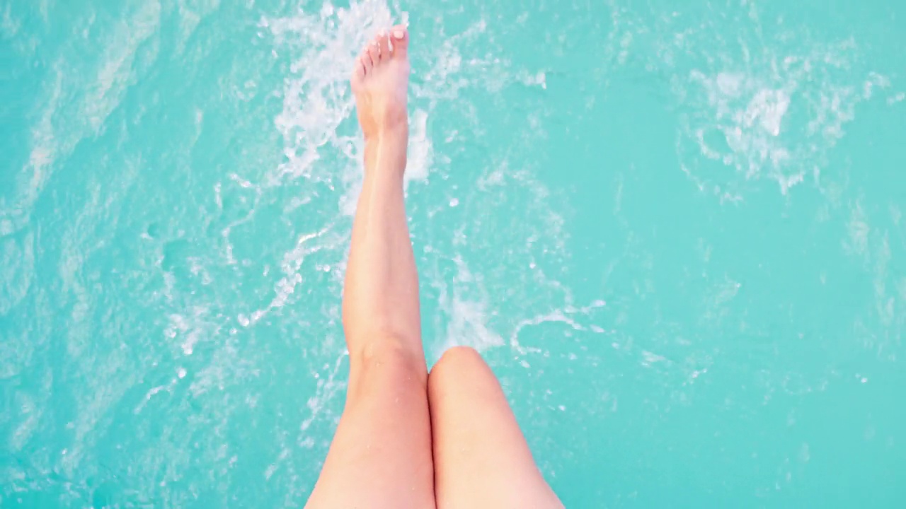 赤脚女日光浴玩脚在纯净的水在室外游泳池俯视图视频下载