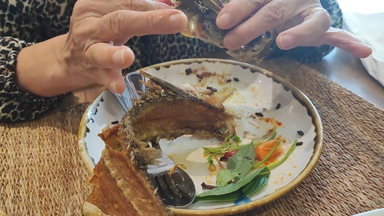 中餐馆里的一道菜，整条炸鲈鱼盖上清蒸小白菜，上面撒上炒蒜和辛辣的泰国辣椒视频下载