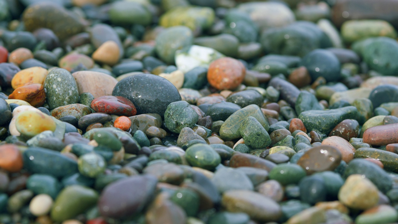 五颜六色的海卵石。小泡沫海浪在卵石滩上破碎。散景。视频下载
