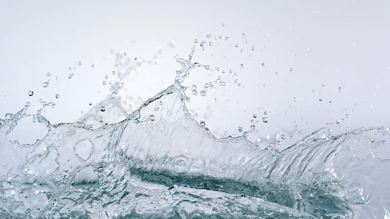 特写镜头和慢动作镜头捕捉到水晶般清澈的水在白色背景下有力地向上溅向液体表面视频下载