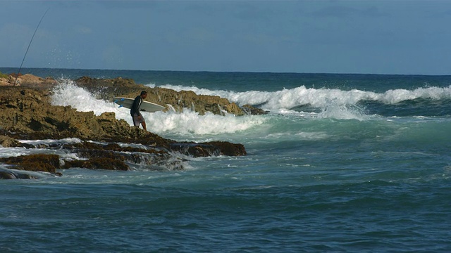 冲浪者通过冲浪爬上岩石视频素材