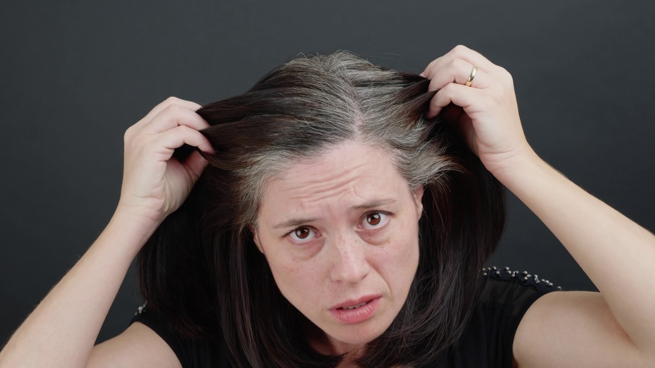 一位中年妇女正在为她的头发变白而哀叹。视频下载