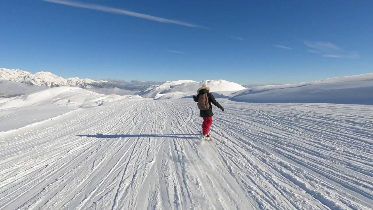 女士滑雪板在一个风景优美的滑雪斜坡与雪山的壮丽景色视频下载