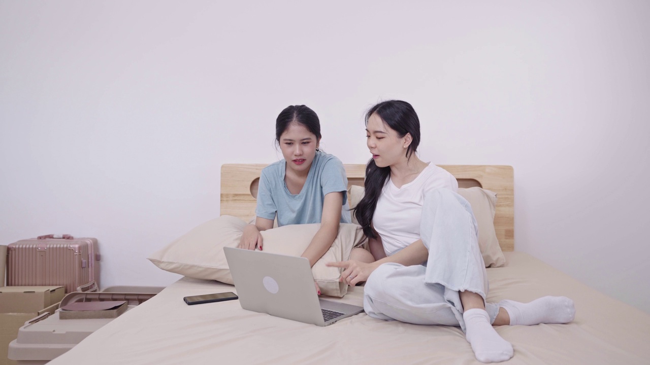 亚洲女性室友、学生或女学生坐在宿舍的床上或地板上用笔记本电脑做作业或复习功课视频下载
