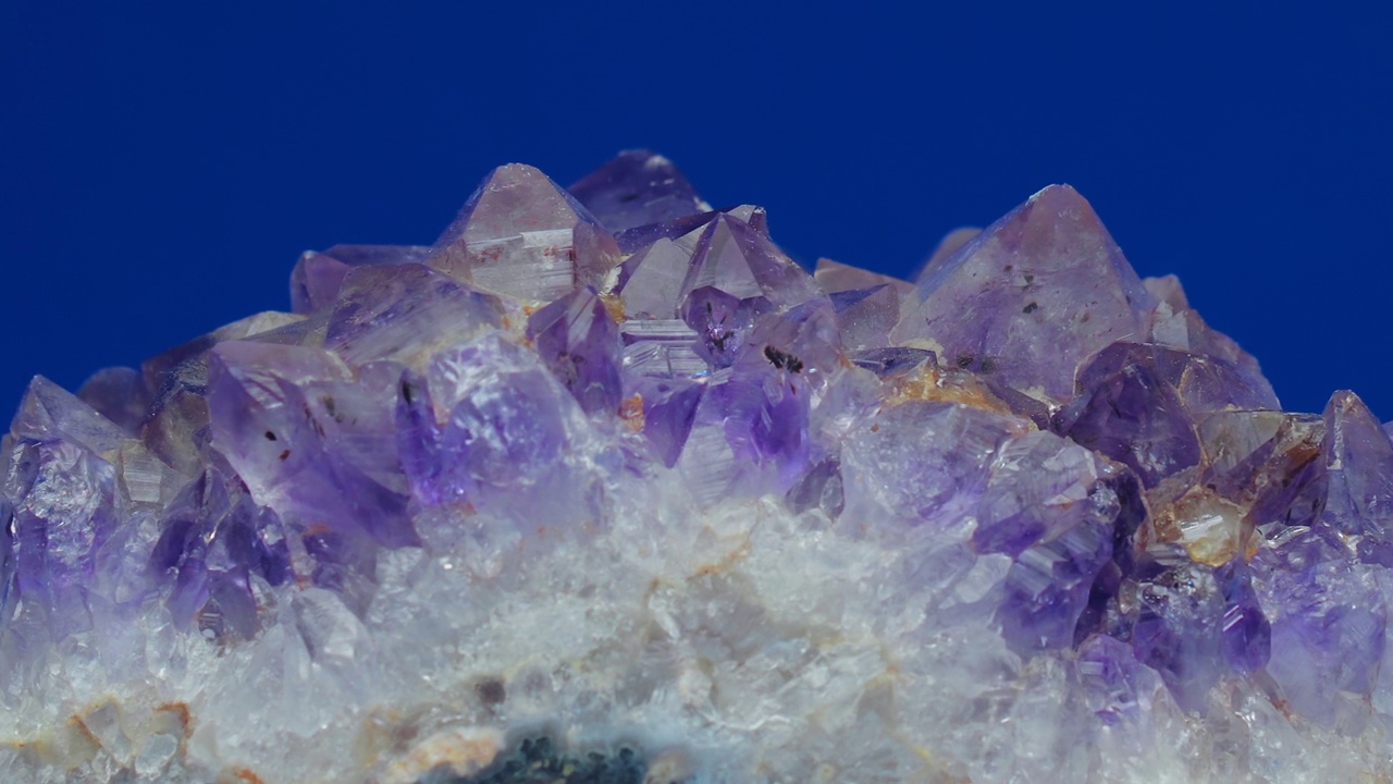 紫水晶石英晶体旋转宏观纹理紫罗兰色孤立宝石在蓝色背景视频下载