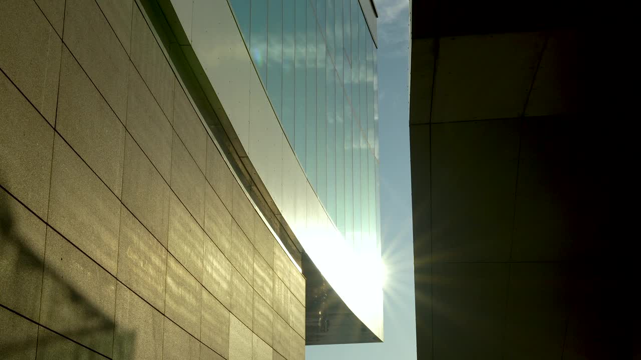 阳光照射在玻璃和石墙反射的现代建筑之间。视频素材