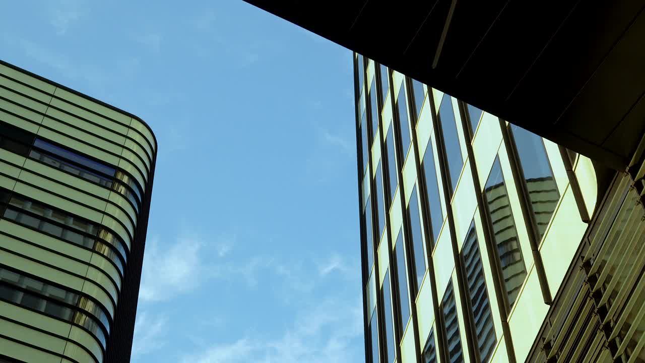 现代摩天大楼的玻璃外墙在蓝天的映衬下反光。视频素材