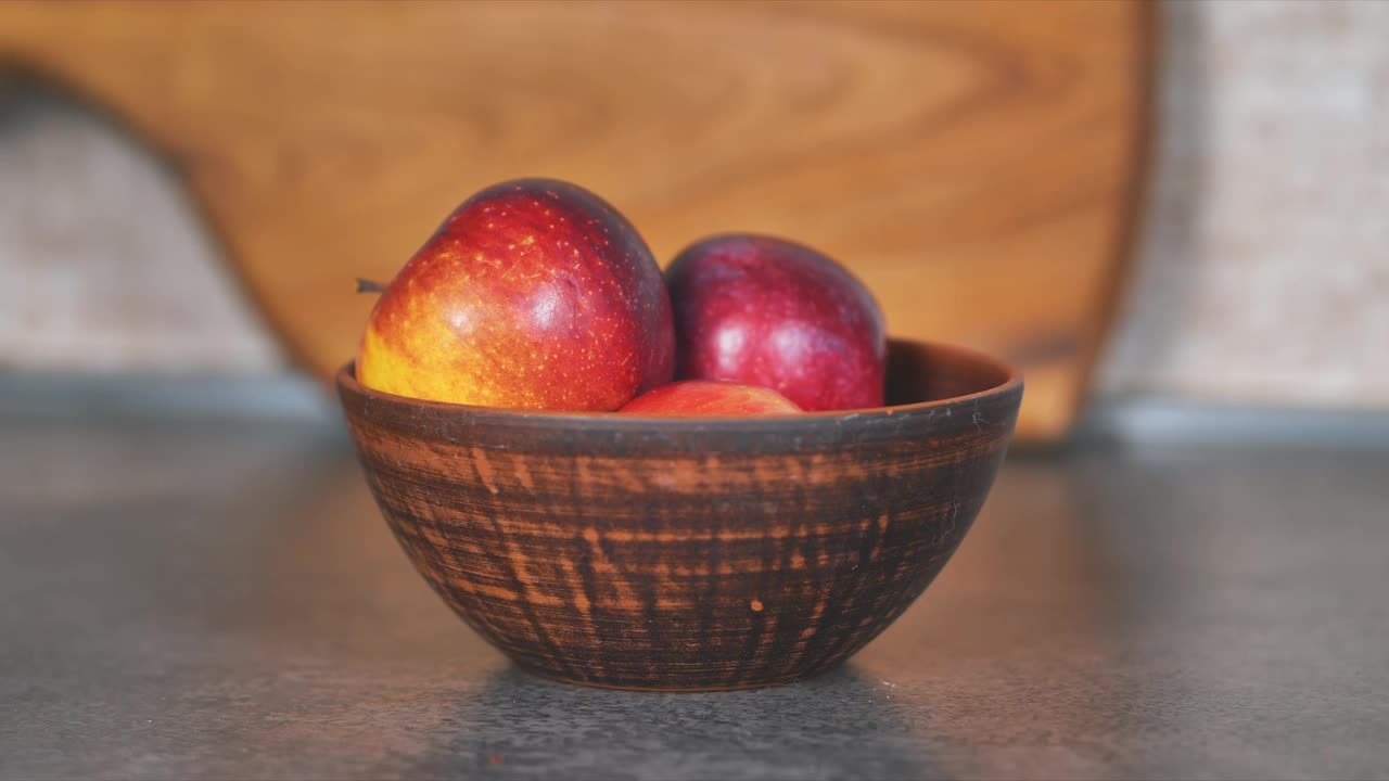 泥盘子里的红苹果。背景是一个由樱桃木制成的大砧板视频下载
